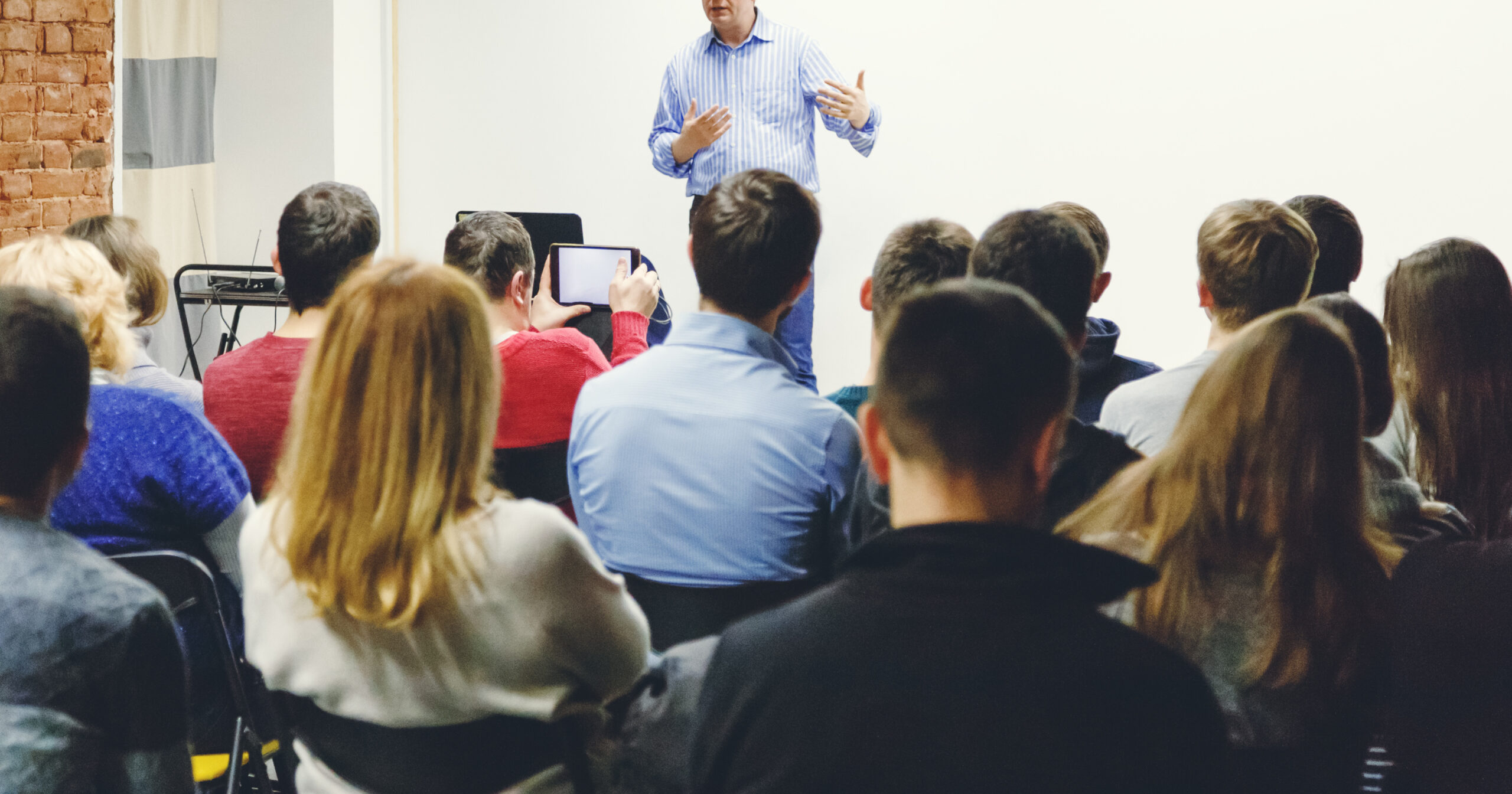 Adult students listen to professor's lecture in small class room